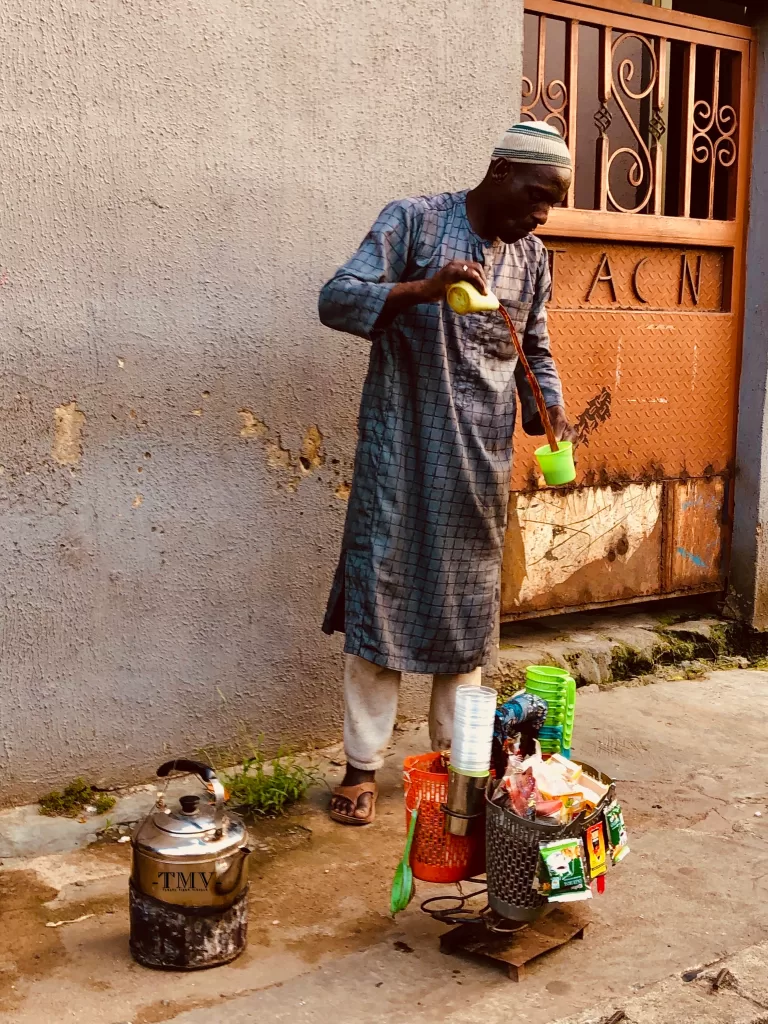 A Mallam (Northern Nigerian) mixing tea for customers