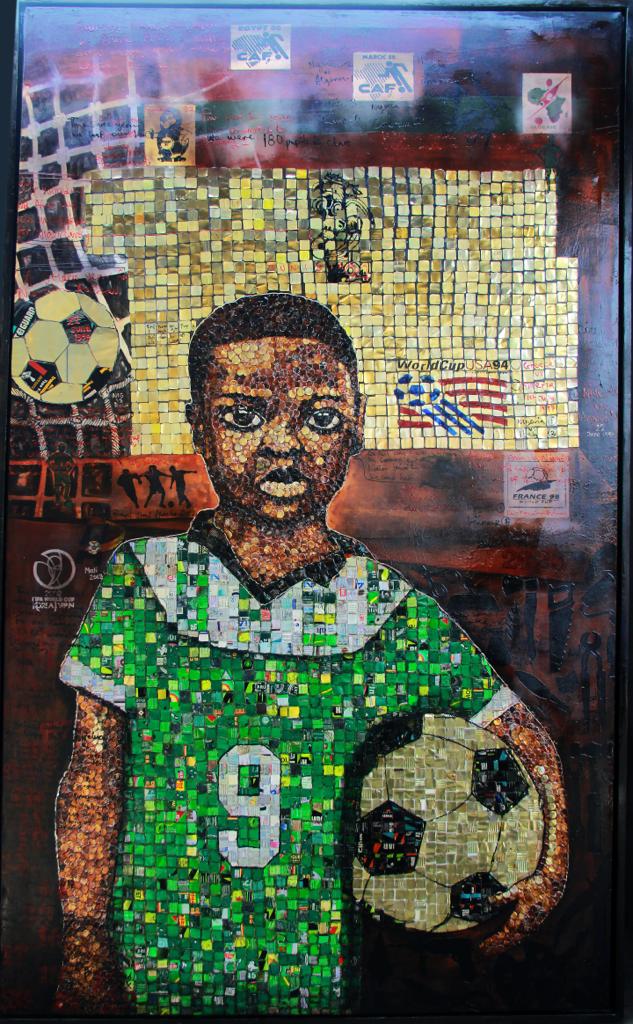 A self portrait of Samson Akinnire made from upcycling materials on canvas. 8 year old Samson is holding a ball wearing a green jersey. It is dated 2023.