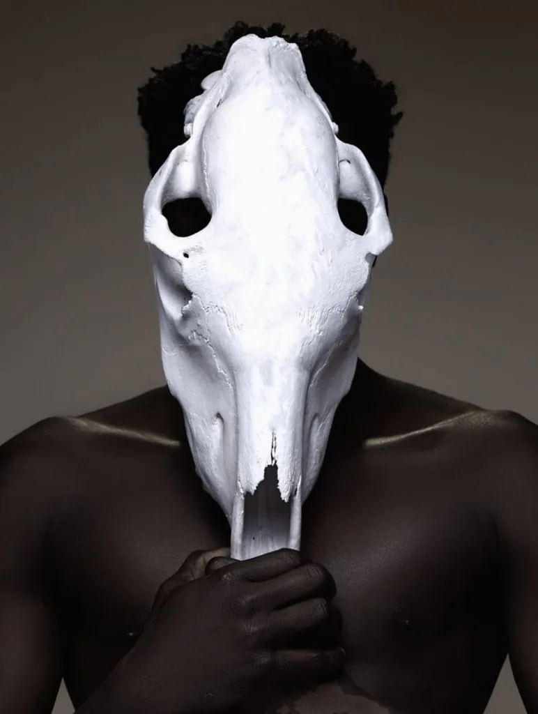 A man placing the buffalo skull atop his face like a mask.